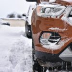 SUV vozidlo jazdiace po zasneženej horskej ceste počas zimného dňa.