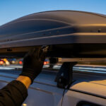 Lacný strešný box na aute s viditeľne zdeformovaným plastovým vekom, ktoré vplyvom tepla nedolieha správne.